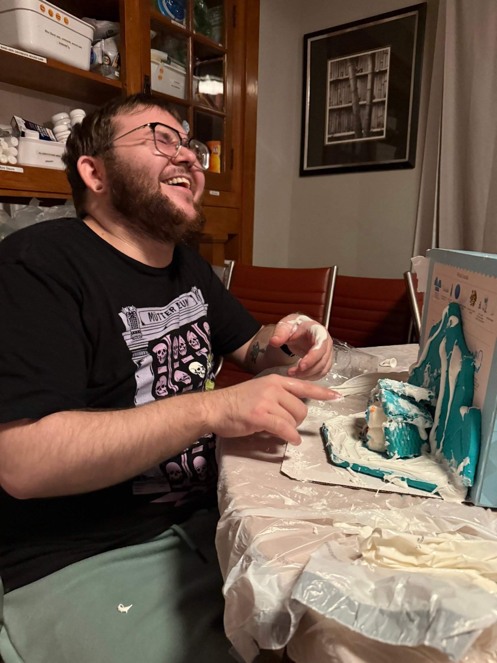 A photo of a quest house guest (the web developer for QH ;) laughing while building a gingerbread house.